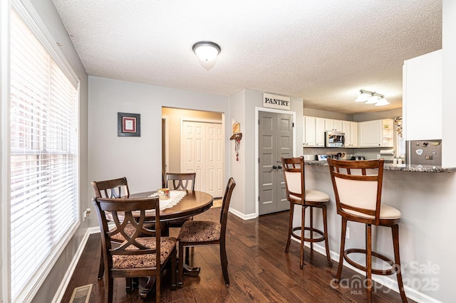 dining room featuring a textured ceiling and dark hardwood / wood-style flooring