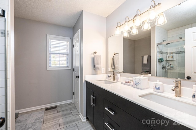 bathroom with an enclosed shower, vanity, a chandelier, and a textured ceiling