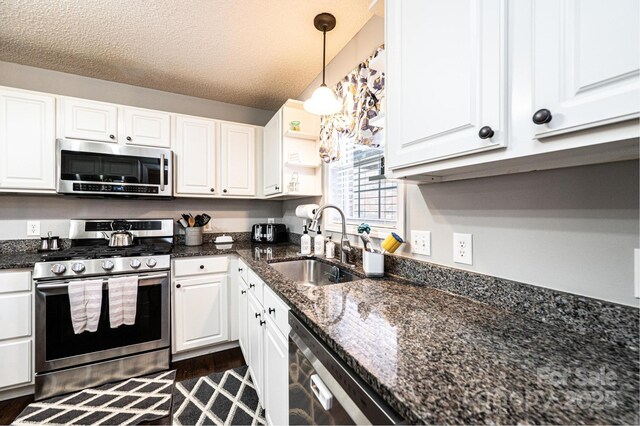 kitchen with sink, decorative light fixtures, appliances with stainless steel finishes, dark stone counters, and white cabinets