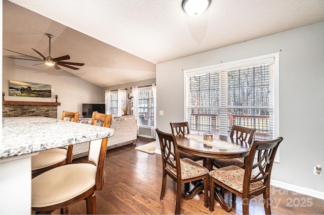 dining room with ceiling fan, lofted ceiling, dark hardwood / wood-style floors, and a textured ceiling