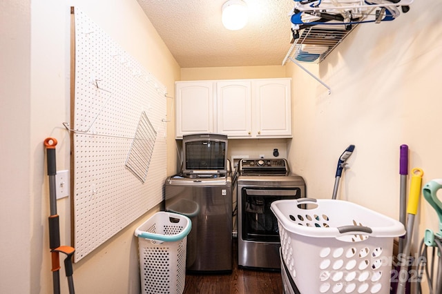 laundry room with independent washer and dryer, cabinets, dark wood-type flooring, and a textured ceiling