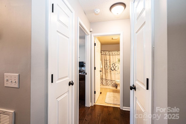 hall featuring dark wood-type flooring and a textured ceiling