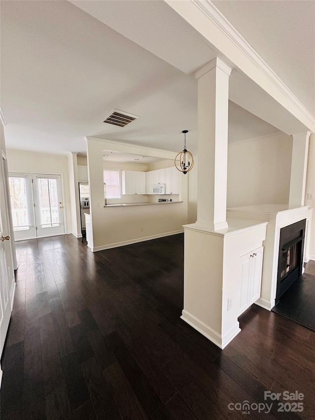 unfurnished living room with dark hardwood / wood-style flooring and decorative columns