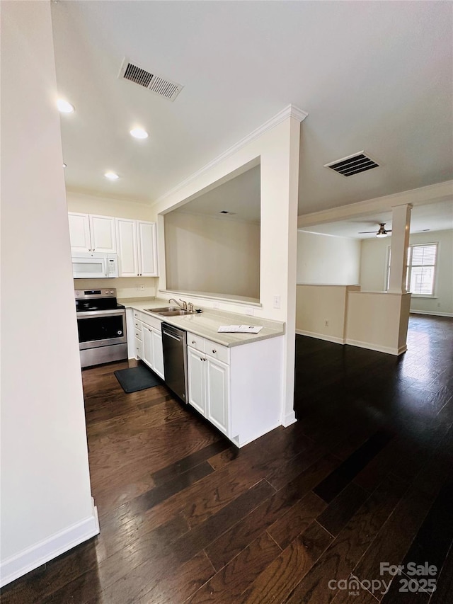 kitchen featuring appliances with stainless steel finishes, sink, white cabinets, and dark hardwood / wood-style flooring