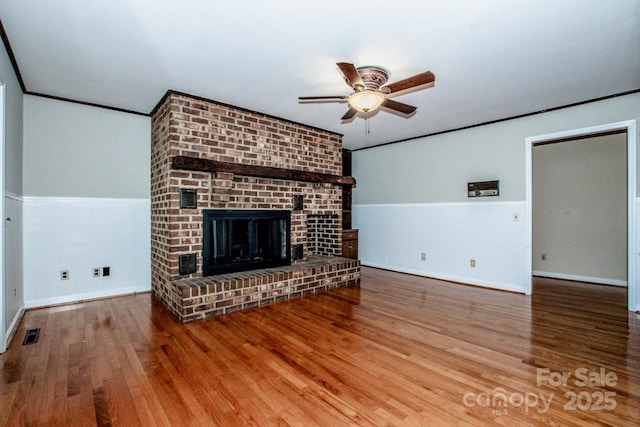 unfurnished living room featuring hardwood / wood-style flooring, ceiling fan, ornamental molding, and a fireplace