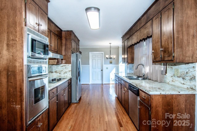 kitchen with sink, appliances with stainless steel finishes, hanging light fixtures, light hardwood / wood-style floors, and decorative backsplash