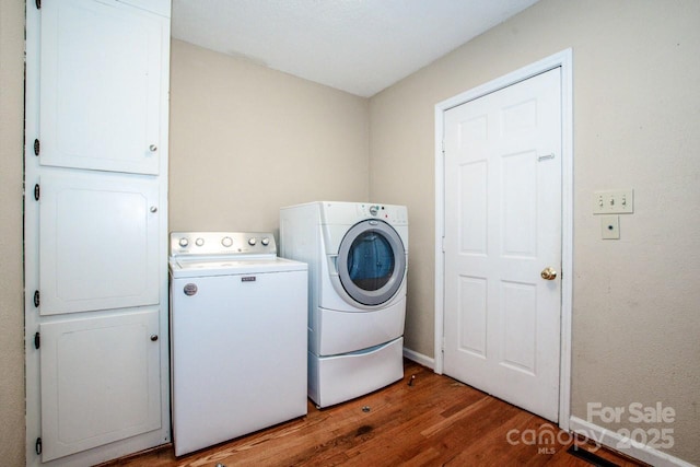 laundry room featuring washer and dryer, hardwood / wood-style flooring, and cabinets