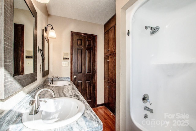 bathroom featuring hardwood / wood-style flooring, vanity, bathtub / shower combination, and a textured ceiling