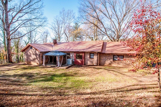 view of front of property featuring central AC, a gazebo, and a front lawn