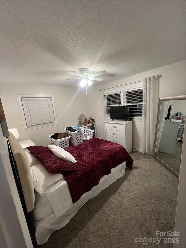 bedroom with ceiling fan, carpet, and a textured ceiling