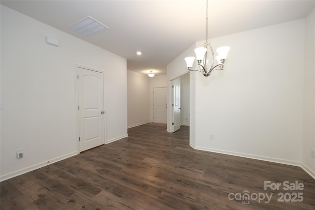 spare room with dark hardwood / wood-style flooring and an inviting chandelier