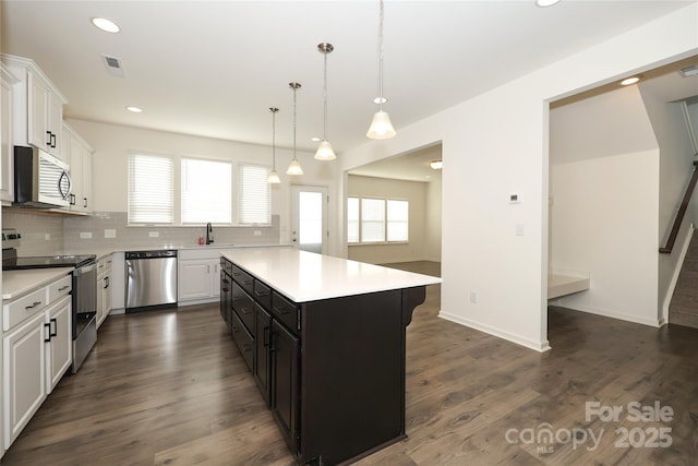 kitchen featuring stainless steel appliances, white cabinetry, a kitchen island, and hanging light fixtures