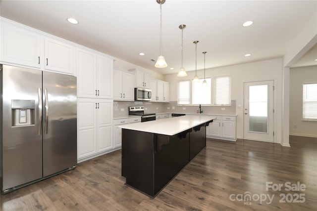 kitchen with pendant lighting, stainless steel appliances, white cabinets, and a kitchen island