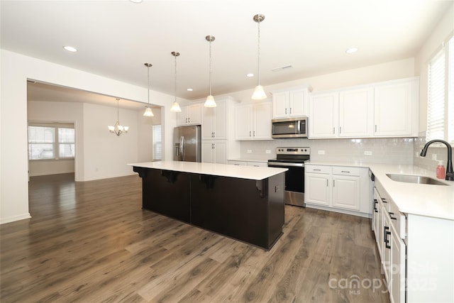 kitchen featuring sink, a center island, pendant lighting, stainless steel appliances, and white cabinets