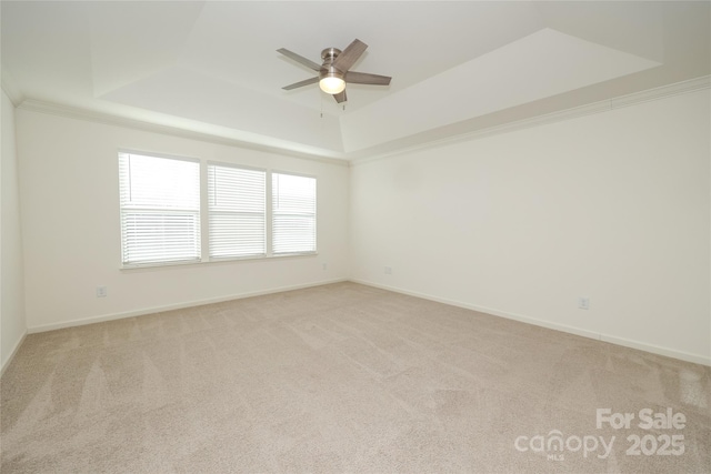 carpeted spare room featuring ornamental molding, a raised ceiling, and ceiling fan