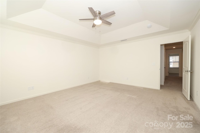 unfurnished room featuring ceiling fan, ornamental molding, a tray ceiling, and light carpet