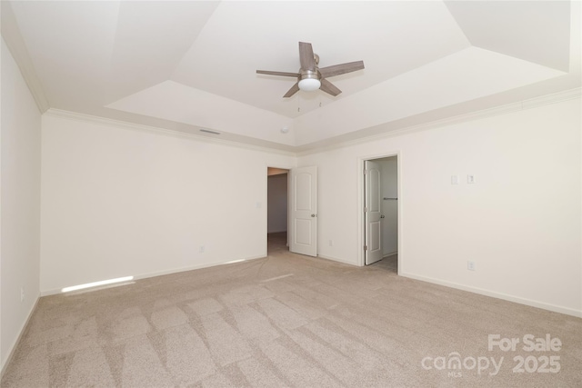 spare room with ceiling fan, light colored carpet, ornamental molding, and a raised ceiling