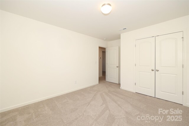 unfurnished bedroom featuring light colored carpet and a closet