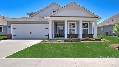 view of front of property featuring a garage, central AC unit, covered porch, and a front lawn