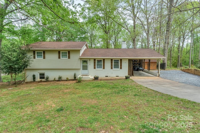 split level home featuring roof with shingles, a front lawn, a chimney, concrete driveway, and an attached carport