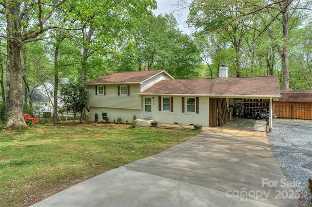 split level home featuring concrete driveway, a carport, a chimney, a front yard, and fence