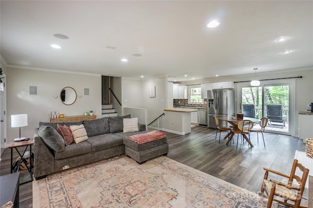 living room featuring recessed lighting, dark wood-style floors, ornamental molding, and stairs