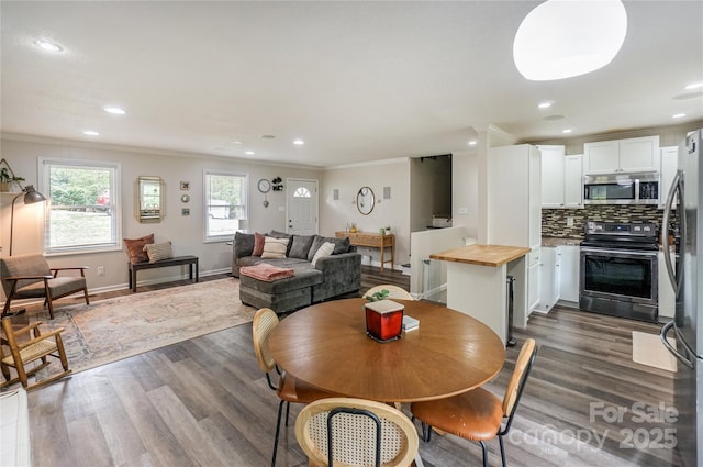 dining space with dark wood-type flooring, baseboards, ornamental molding, and recessed lighting