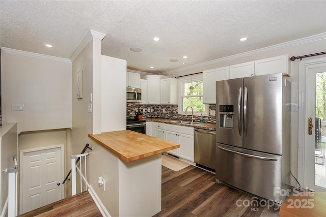 kitchen featuring white cabinetry, dark wood-type flooring, decorative backsplash, stainless steel appliances, and a sink