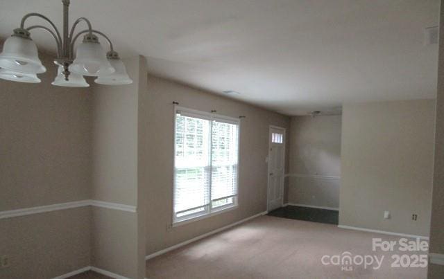 spare room with a chandelier and carpet