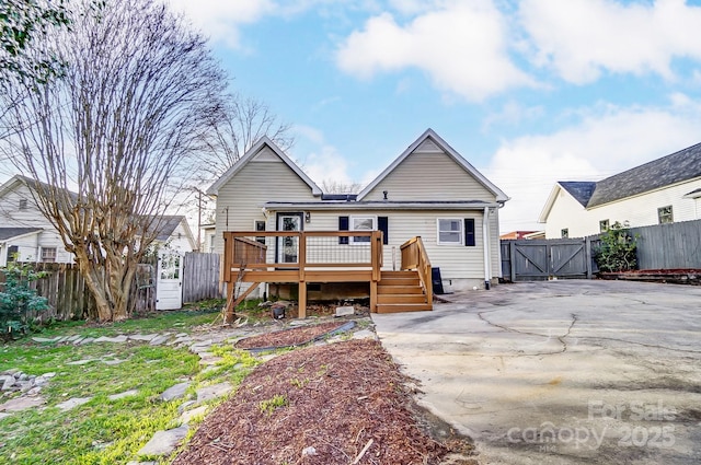 back of property with a gate, fence, and a deck