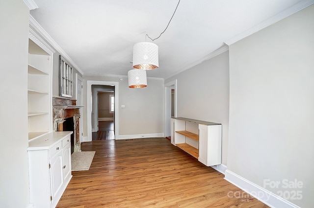 unfurnished living room featuring light wood-style floors, a fireplace with flush hearth, ornamental molding, and baseboards