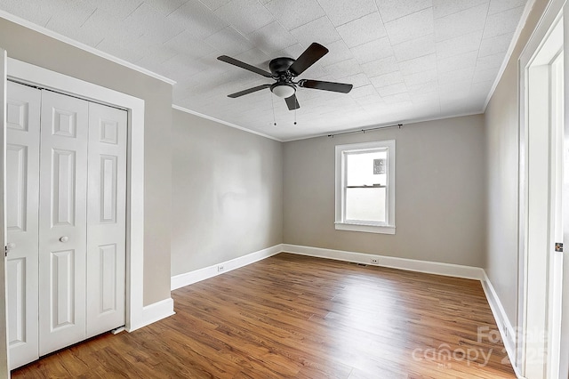 unfurnished bedroom featuring crown molding, baseboards, and wood finished floors