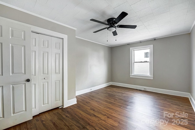 unfurnished bedroom with ornamental molding, dark wood-style flooring, a closet, and baseboards