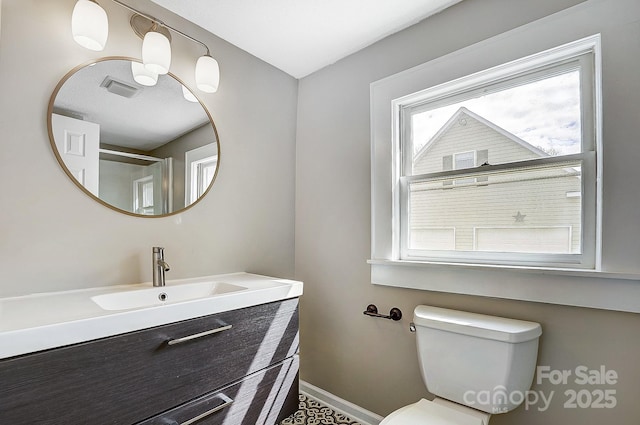 bathroom featuring toilet, vanity, visible vents, and baseboards