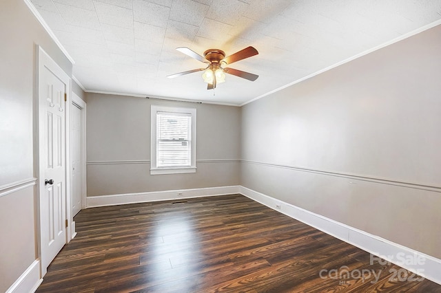 spare room with ornamental molding, dark wood-style flooring, a ceiling fan, and baseboards