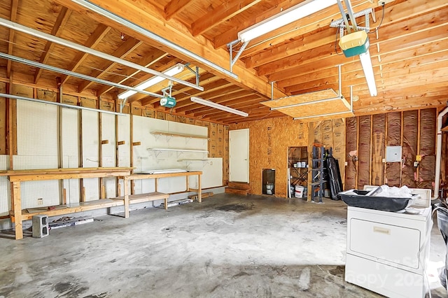 garage with a garage door opener, washer / clothes dryer, and a workshop area