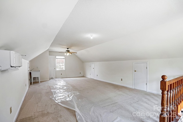 additional living space featuring light carpet, baseboards, a textured ceiling, and lofted ceiling