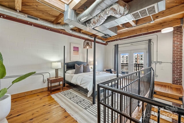 bedroom with light hardwood / wood-style flooring, french doors, and brick wall