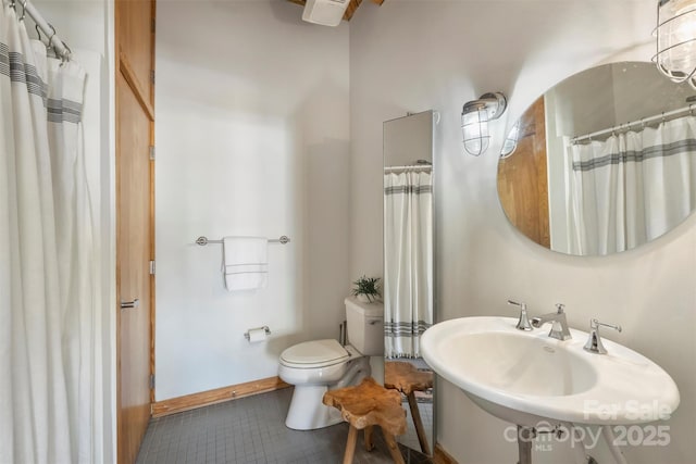 bathroom with a shower with curtain, sink, toilet, and tile patterned flooring