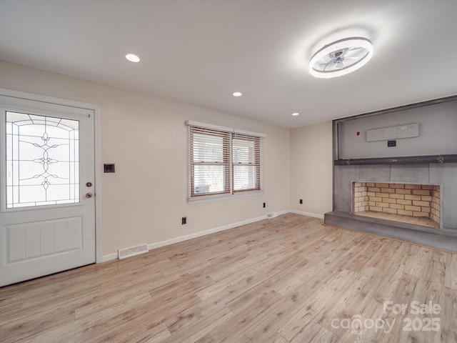 unfurnished living room featuring a tile fireplace and light hardwood / wood-style floors