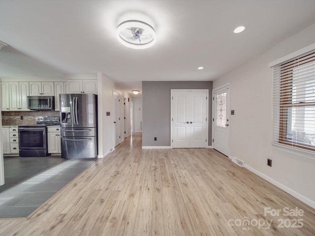 kitchen with appliances with stainless steel finishes, a healthy amount of sunlight, white cabinets, and decorative backsplash