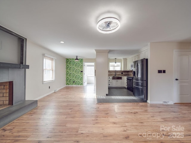 unfurnished living room with a fireplace, sink, and light hardwood / wood-style flooring