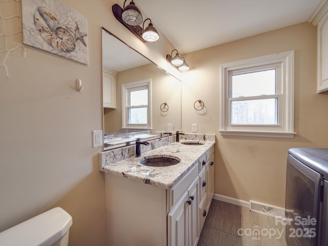 bathroom featuring washing machine and clothes dryer, vanity, and toilet