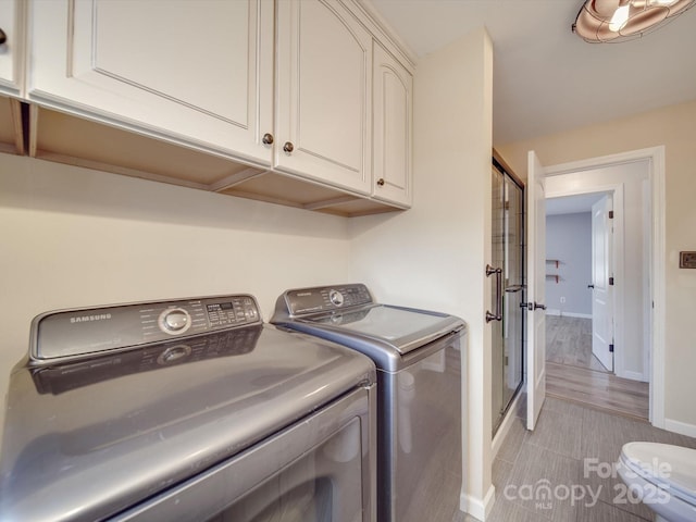 clothes washing area with independent washer and dryer and cabinets