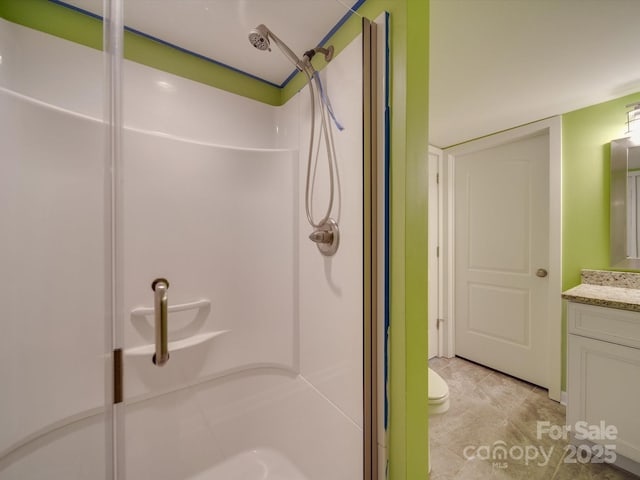 bathroom with vanity, toilet, and a shower with door