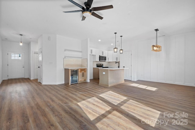 unfurnished living room with sink, light hardwood / wood-style flooring, beverage cooler, and ceiling fan