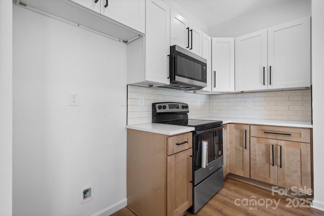 kitchen featuring white cabinetry, decorative backsplash, light hardwood / wood-style flooring, and appliances with stainless steel finishes