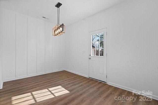 unfurnished dining area featuring an inviting chandelier and dark hardwood / wood-style flooring