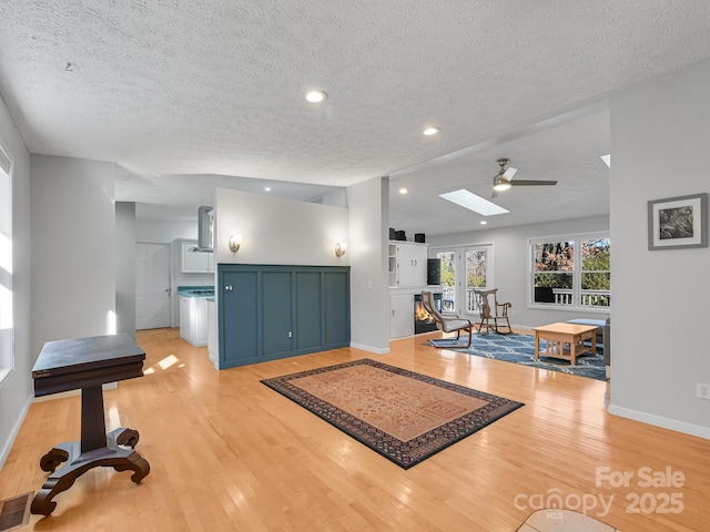 workout room featuring a skylight, light hardwood / wood-style flooring, and a textured ceiling