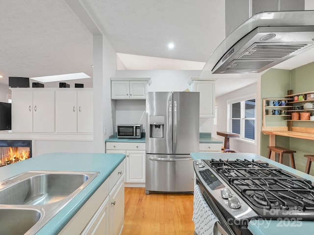 kitchen featuring white cabinetry, appliances with stainless steel finishes, light hardwood / wood-style floors, and exhaust hood